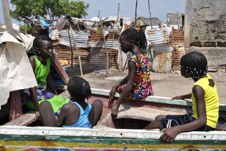 Die 11-jährige Seynabou (ganz links im grünen Kleid) und ihre Freundinnen spielen in einem Fischerboot. (Foto: Ousmane Kobar / Fastenopfer)